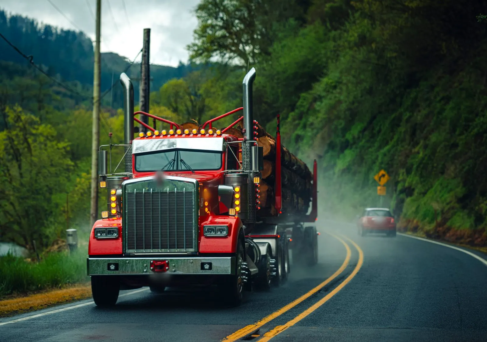 A red log truck on a misty Oregon highway